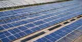Deretan panel surya biru di atap gedung olahraga