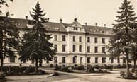 Gedung sekolah pada tahun 1985 – foto arsip berwarna sepia dengan pohon-pohon pinus dan taman
