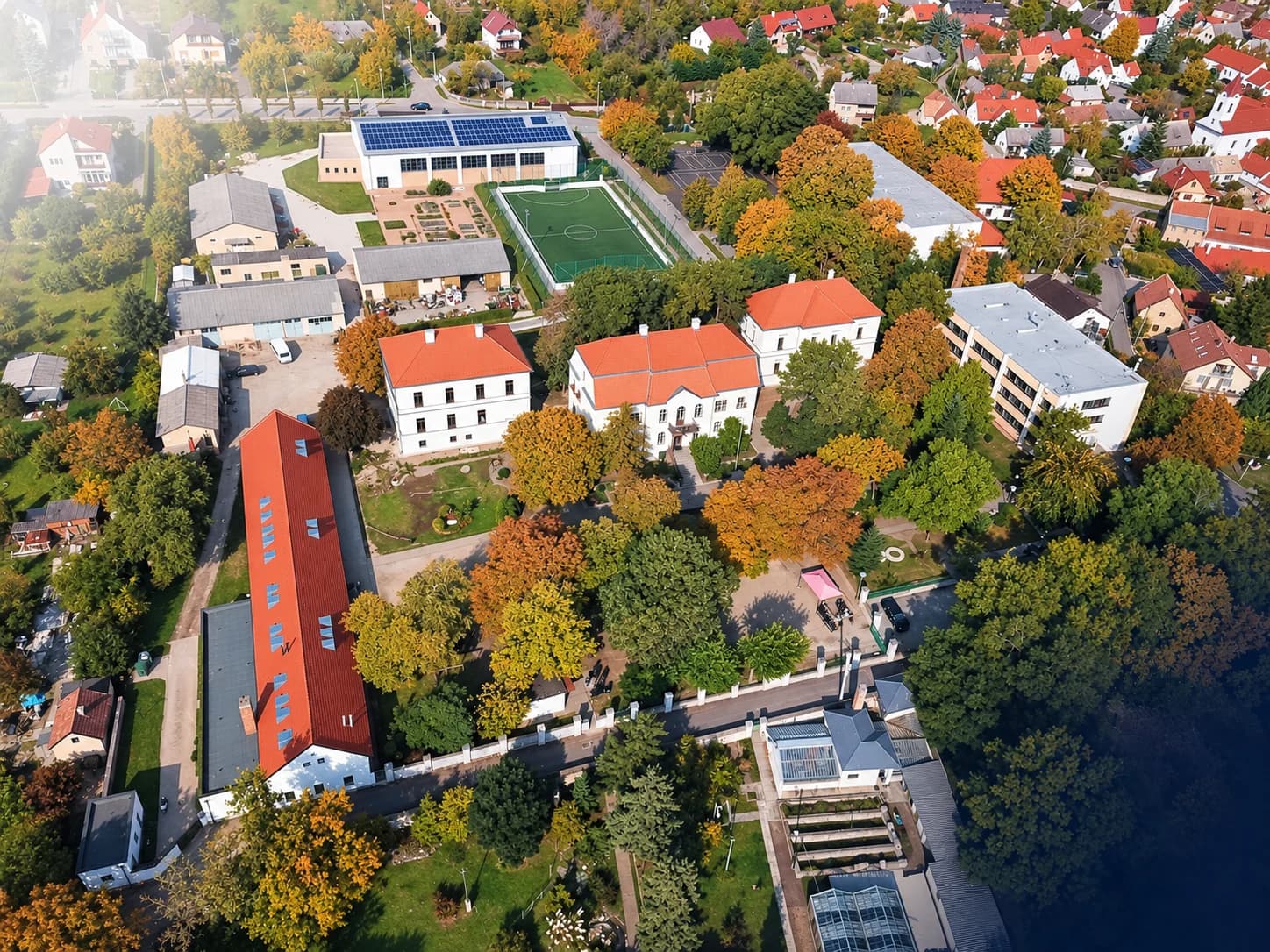 Légifelvétel a Szent Benedek iskola napelemes tetejű sportcsarnokáról, mögötte a Balaton vitorlásokkal és egy kéttornyú templom