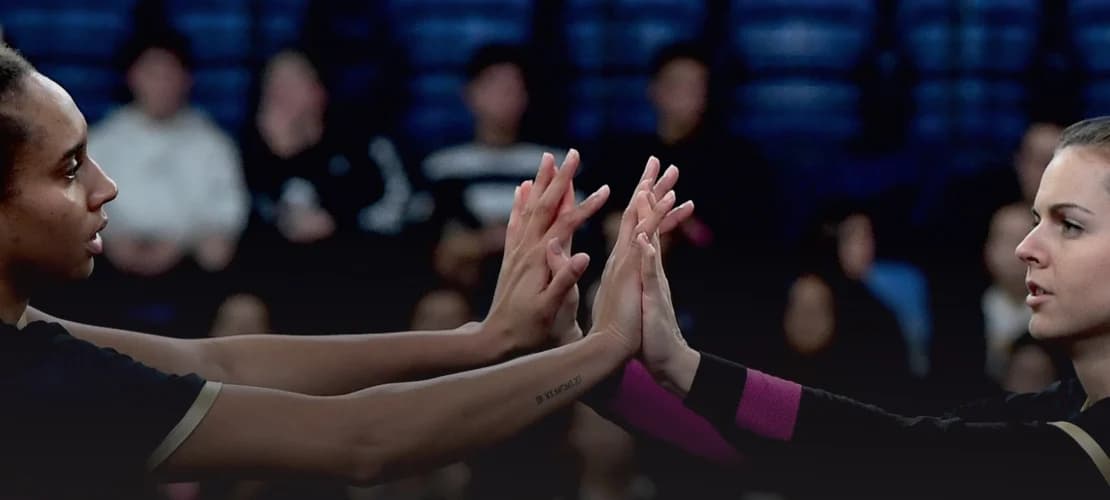 A Szent Benedek röplabdázó lányai összekarolva, csapatkörben a sportcsarnokban